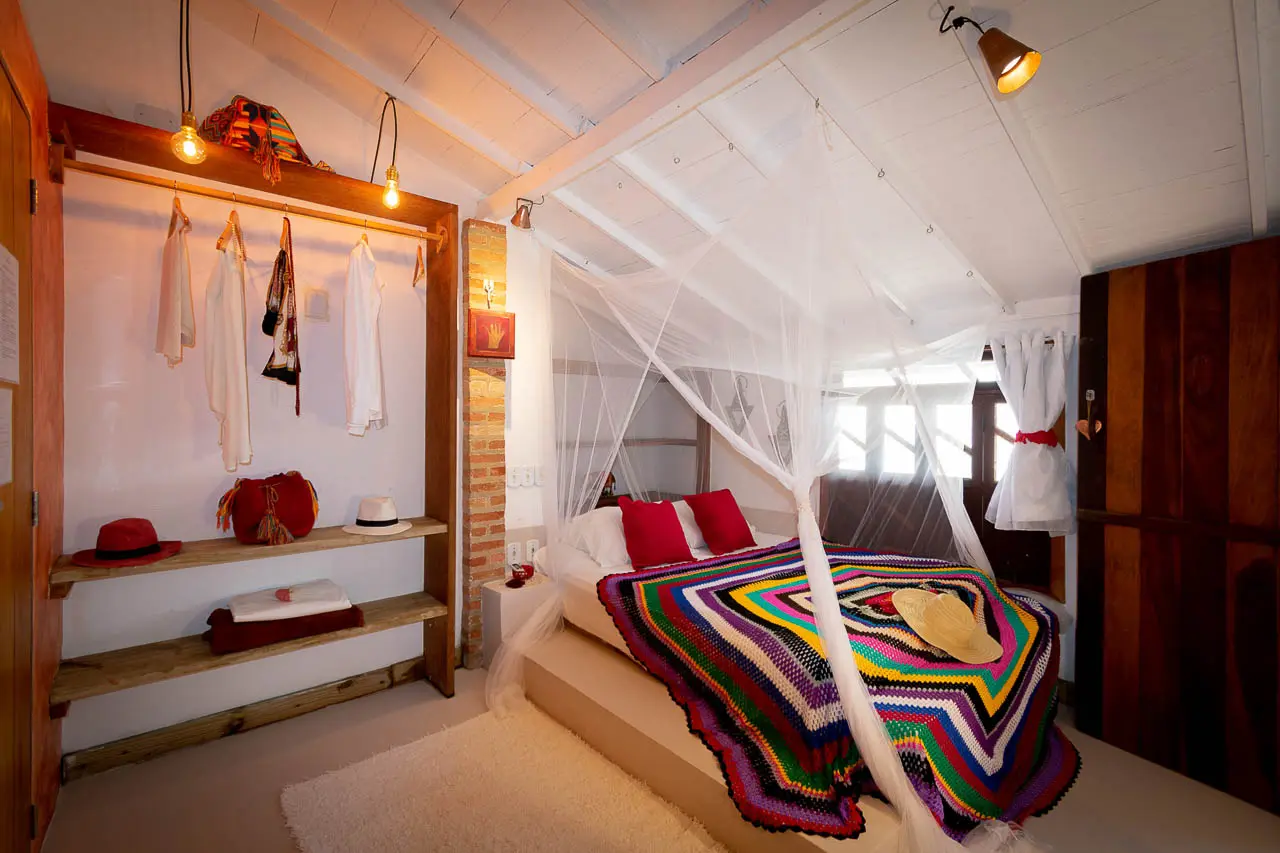 Suíte Hippie Chic com cama baixa, cortinado e manta colorida