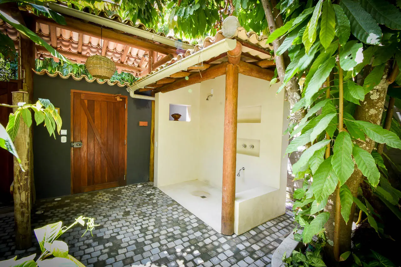 Ducha externa com piso de pedra e plantas