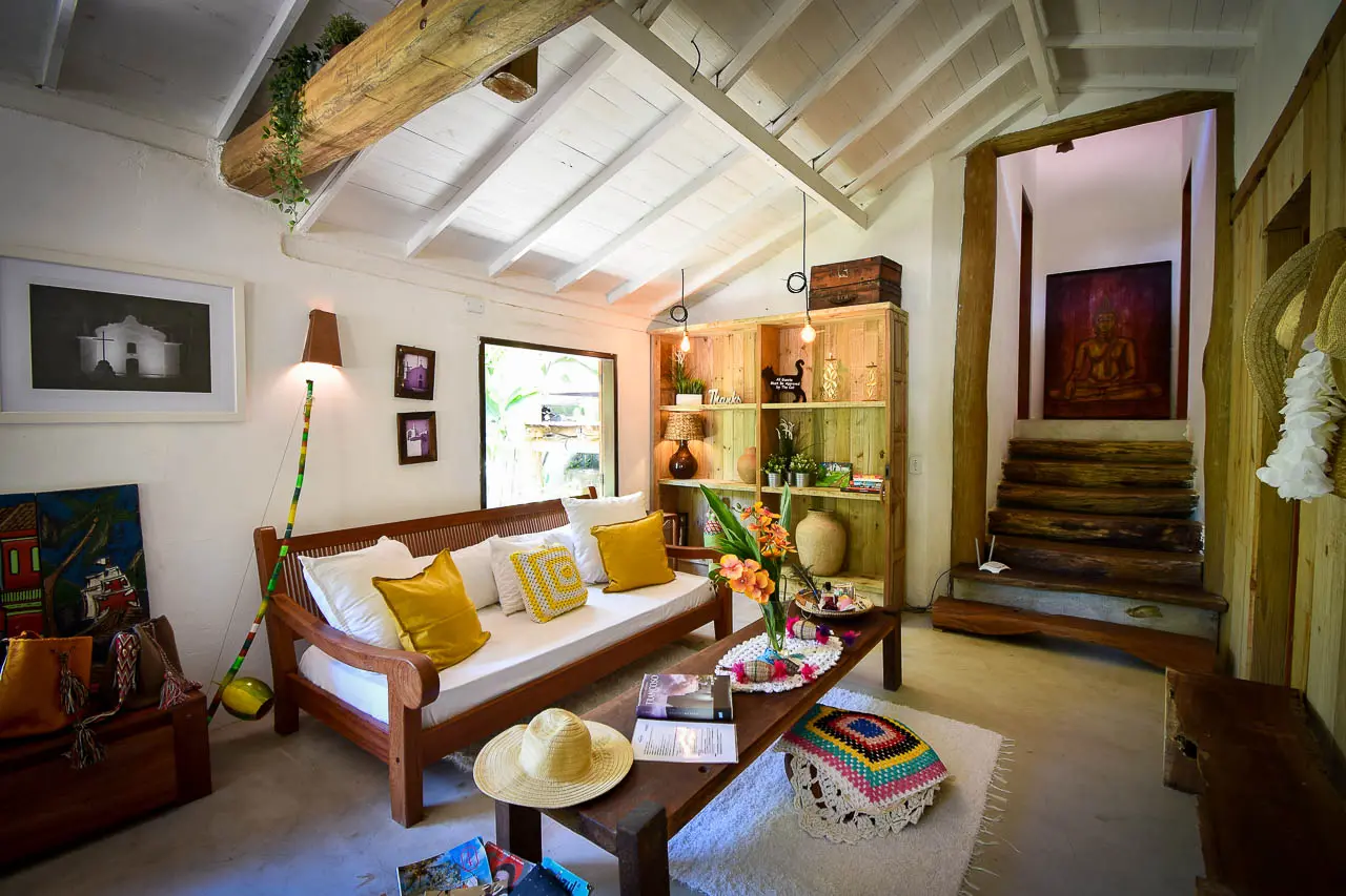 Sala com sofá de madeira e escada para as suítes