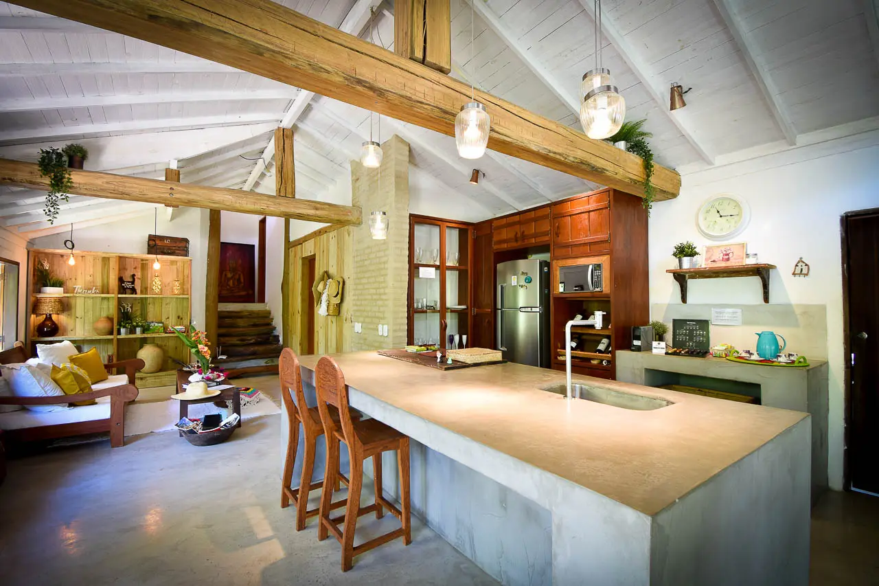 Cozinha integrada com ilha de cimento e banquetas